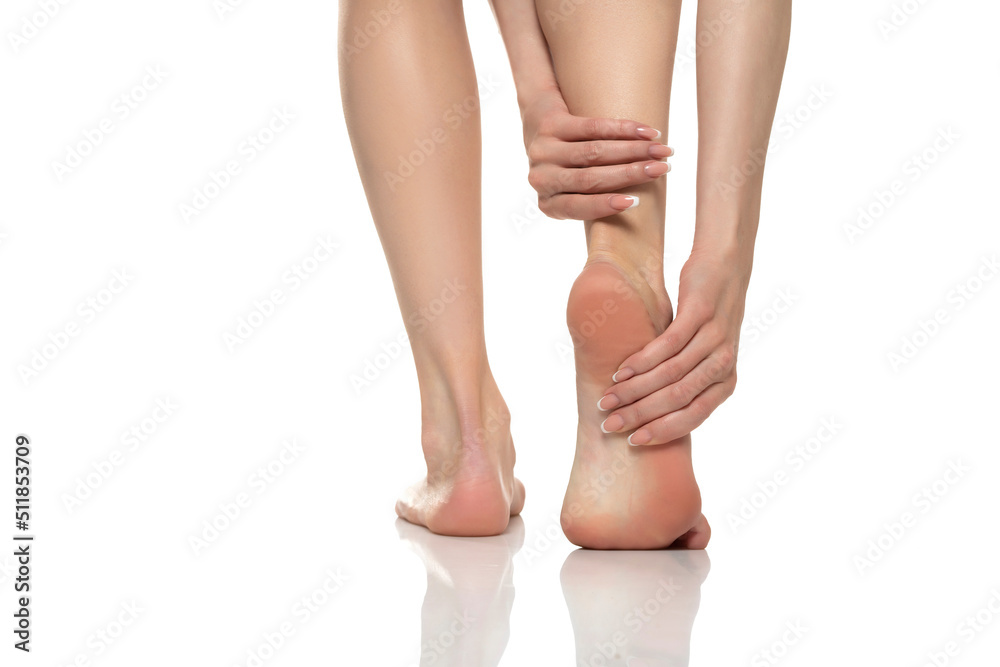 Foot pain in women on a white studio background. Pain concept