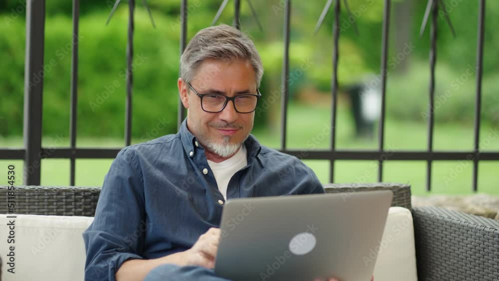 Man working with laptop computer outdoor, sitting in garden at home, . managing business online from home office. Portrait, happy confident smile.