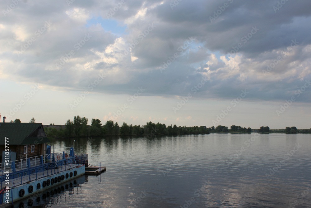 Obraz premium river pier for boats on the river bank evening sky clouds thunderclouds