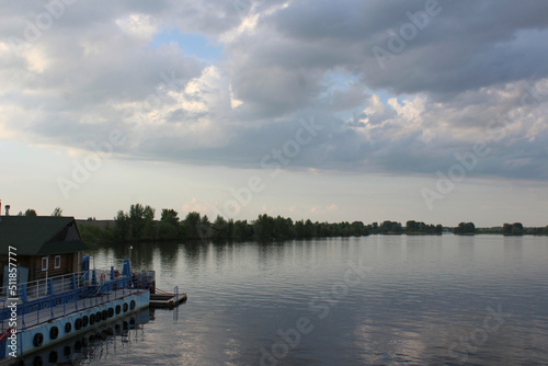 river pier for boats on the river bank evening sky clouds thunderclouds © Татьяна Фоевцева