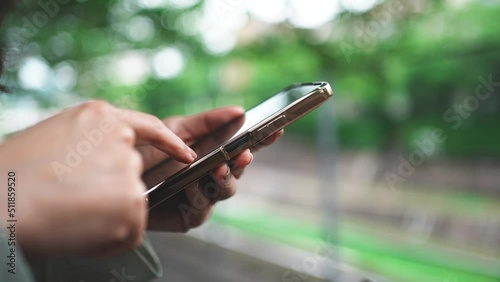スマホを持つ女性の手元と緑ぼかし背景