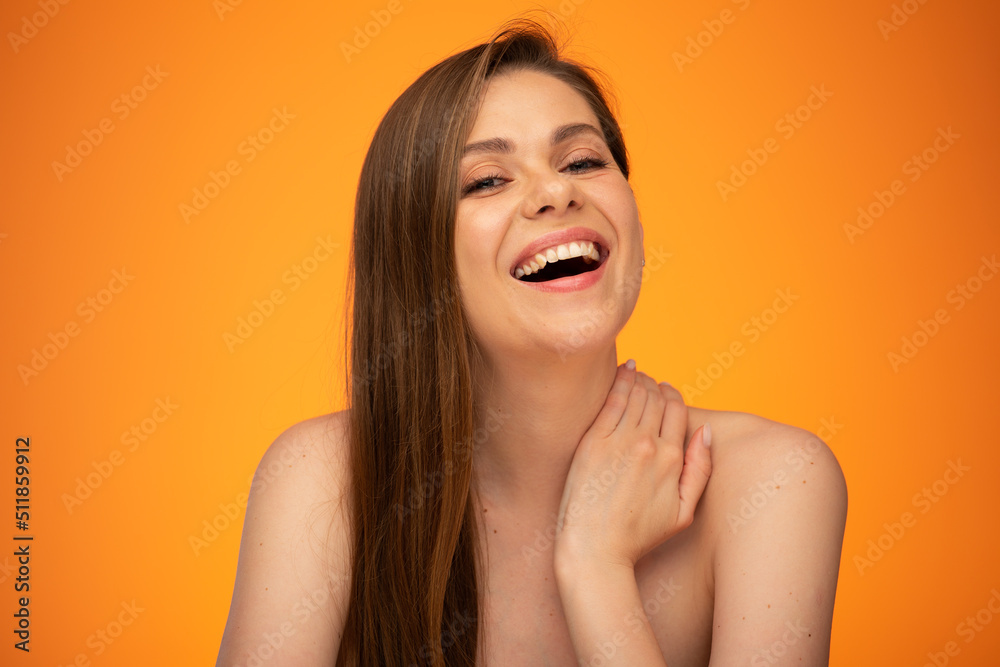 Laughing woman with long hair and bare shoulders touching her neck. isolated female close up portrait on orange background. Laughing woman with long hair and bare shoulders touching her neck. isolated female close up portrait on orange background.