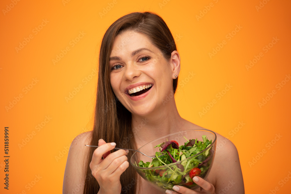 Smiling woman with naked shoulders holding bowl with green salad isolated on orange yellow background. Smiling woman with naked shoulders holding bowl with green salad isolated on orange yellow background.