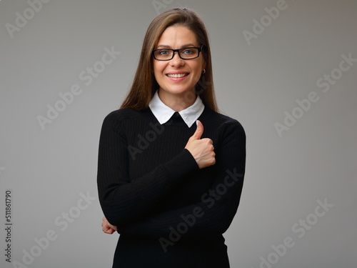 Smiling happy woman in black business suit wearing glasses showing thumb up, isolated female portrait.