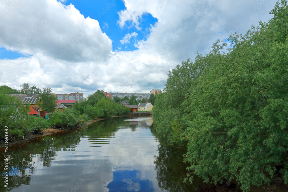 Beautiful summer view of the river in the city with overgrown banks. Russia, Arkhangelsk, Solombalka River