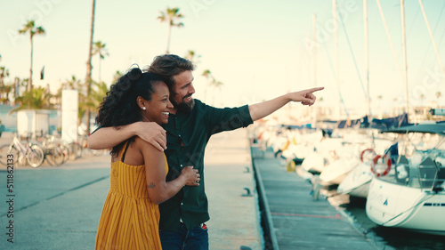 Close-up of young happy man and woman joyfully hugging on the seashore on a yacht background. Closeup, joyful date of a young interracial couple.