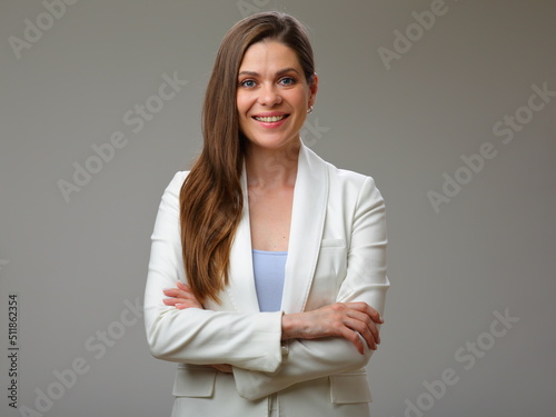 Young smiling woman in white suit standing with crossed arms, studio isolated portrait.