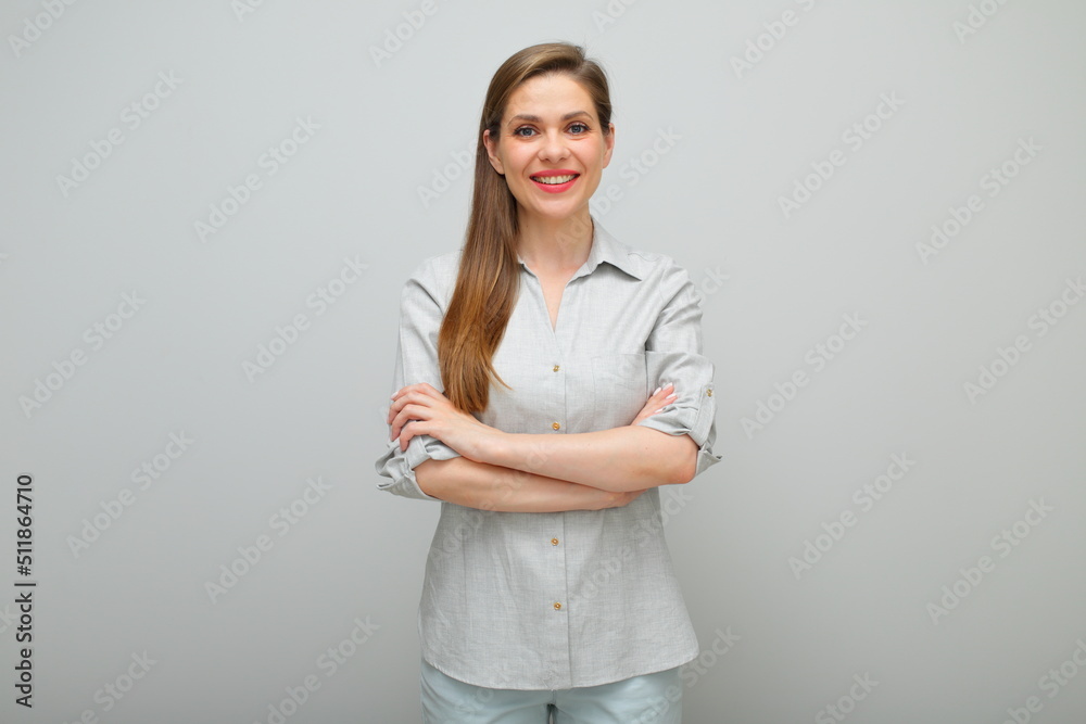 Smiling woman standing with arms crossed, isolated female studio portrait, young lady dressed pants and gray shirt Smiling woman standing with arms crossed, isolated female studio portrait, young lady dressed pants and gray shirt