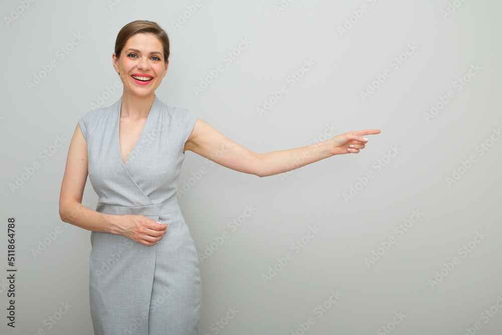 Smiling business woman with short hairstyle pointing finger to copy space, isolated female studio portrait, young business lady in gray dress. Smiling business woman with short hairstyle pointing finger to copy space, isolated female studio portrait, young business lady in gray dress.