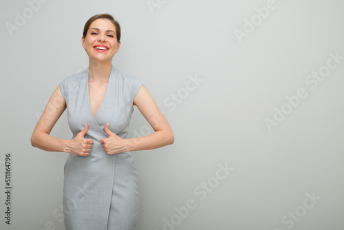 Young business woman with short hairstyle showing thumds up, isolated female studio portrait, young business lady in gray dress. photo