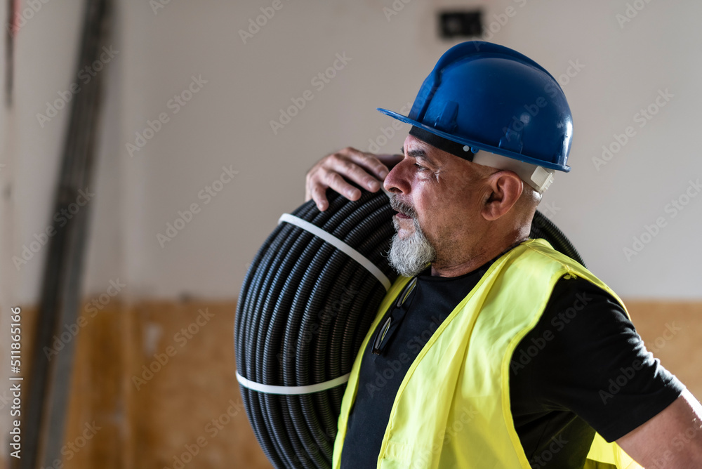 Construction worker poses with corrugated pipe destined for the electrical installation of a home Construction worker poses with corrugated pipe destined for the electrical installation of a home