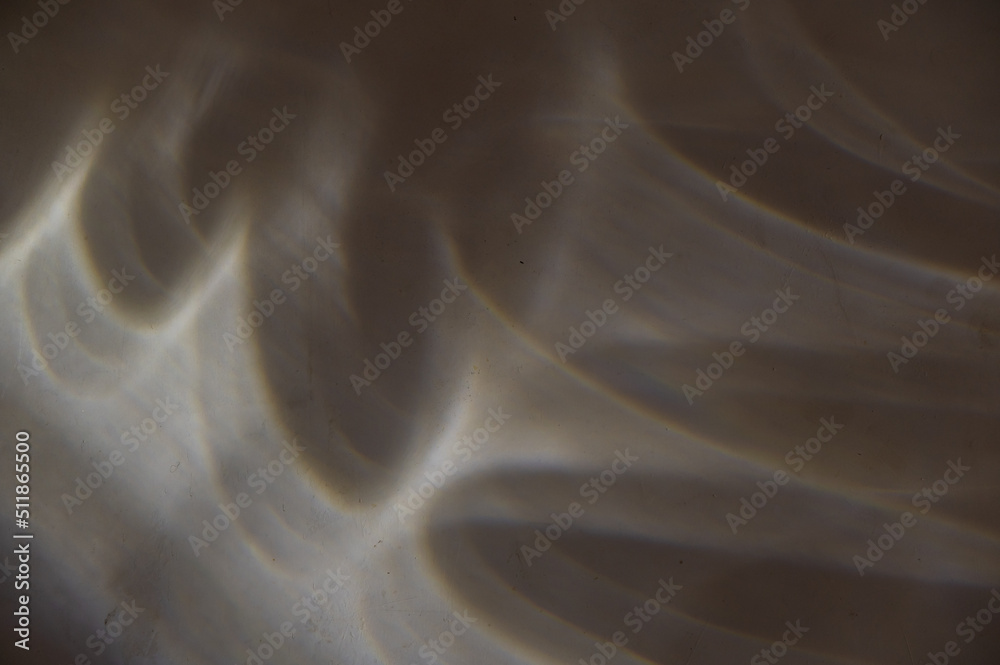 Curved lines of sunlight on a dark stone wall. Light shapes and lines of different shapes. Gray plastered wall. Abstract multi-tasking background for different design tasks. Selective focus. Curved lines of sunlight on a dark stone wall. Light shapes and lines of different shapes. Gray plastered wall. Abstract multi-tasking background for different design tasks. Selective focus.