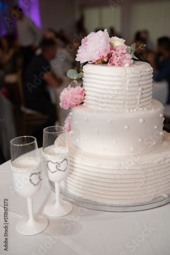 Wedding cake covered with white sugar and champagne love glasses