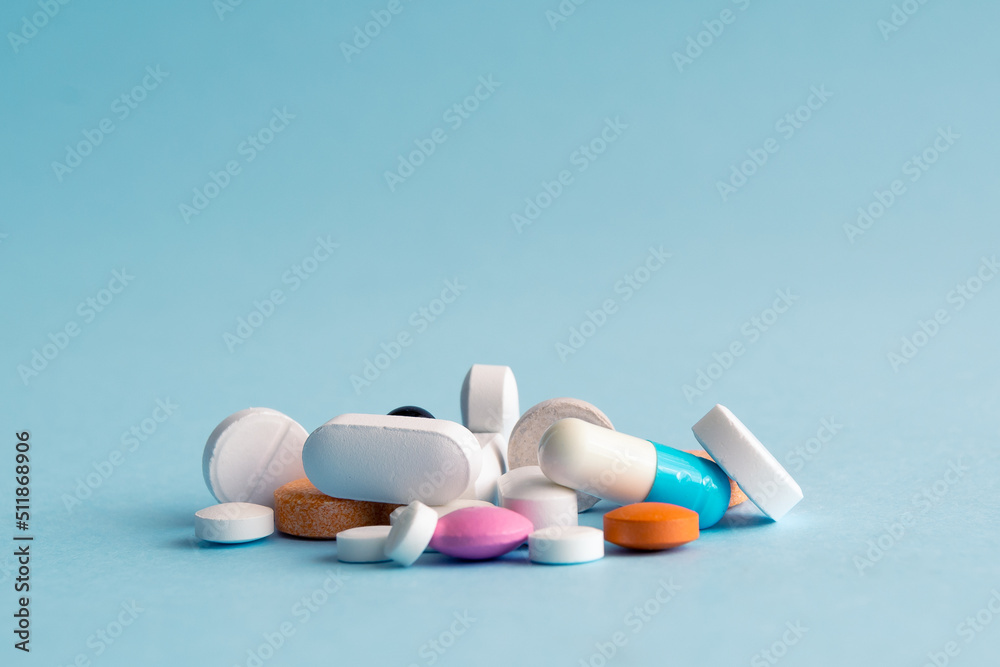 Heap of of colorful pills tablets and capsules on blue background with copy space for text. Heap of of colorful pills tablets and capsules on blue background with copy space for text.