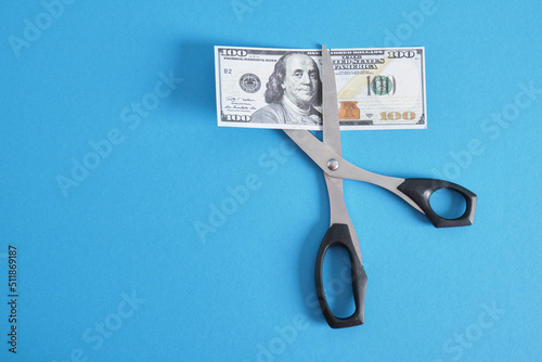 scissors and a bill of 100 dollars on a blue background