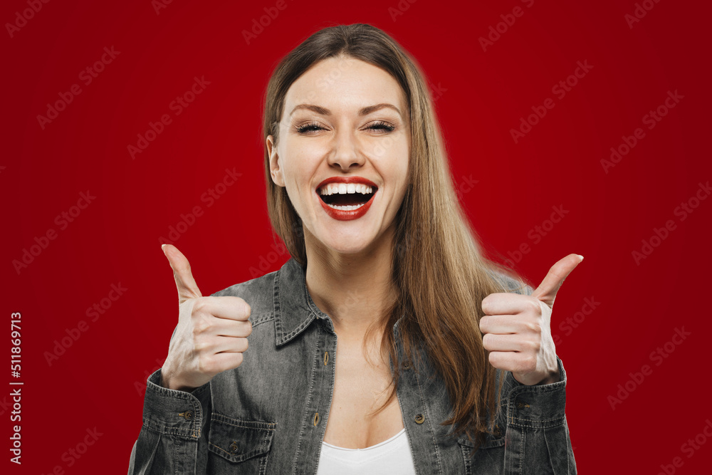 Portrait of happy young student girl showing thumbs up isolated on red background Portrait of happy young student girl showing thumbs up isolated on red background