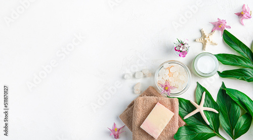 Spa composition with cream, soap, towel and salt on a white background. Top view, copy space.