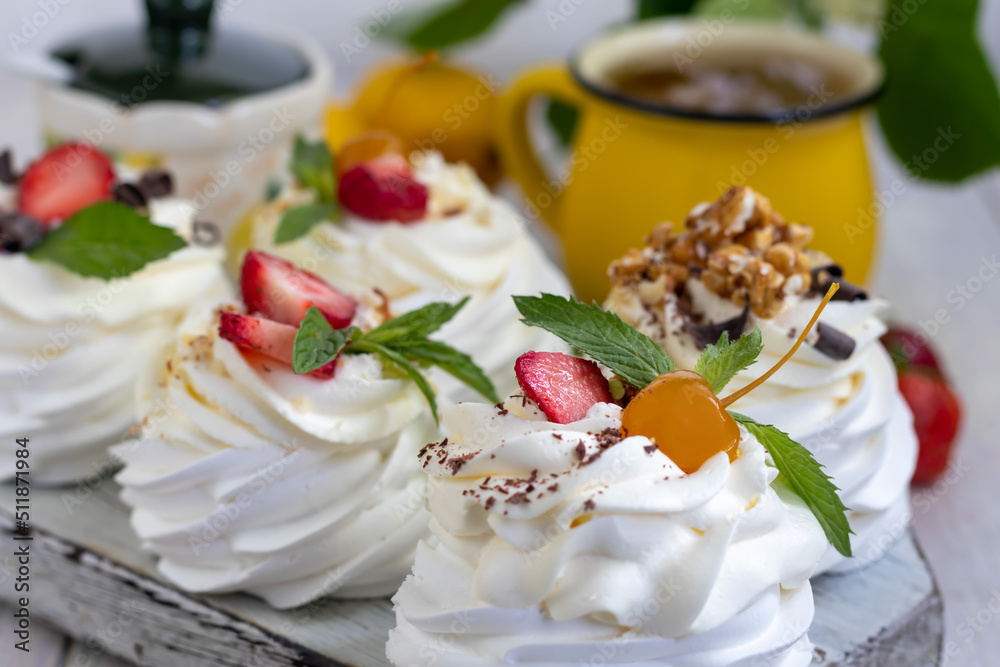 Pavlova meringue cakes with whipped cream and fresh strawberries, mint leaves. Selective focus. Pavlova meringue cakes with whipped cream and fresh strawberries, mint leaves. Selective focus.