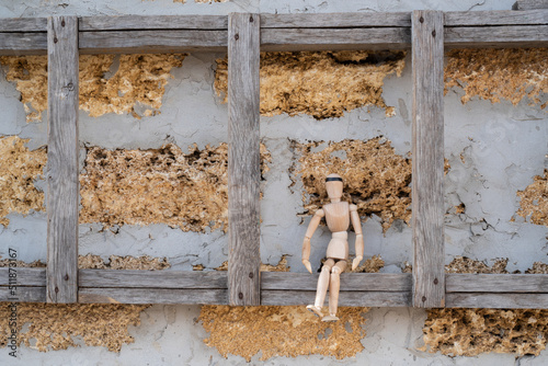 Wooden mannequin sitting on the stepladder in the construction, horizontal photo 