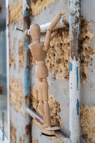Wooden mannequin close-up climbing on ladder in the construction, vertical photo 