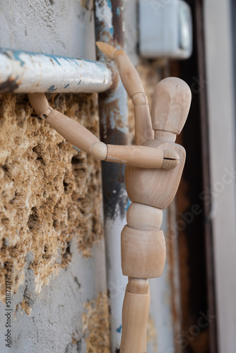 Wooden mannequin close-up climbing on pipe in the construction, vertical photo 