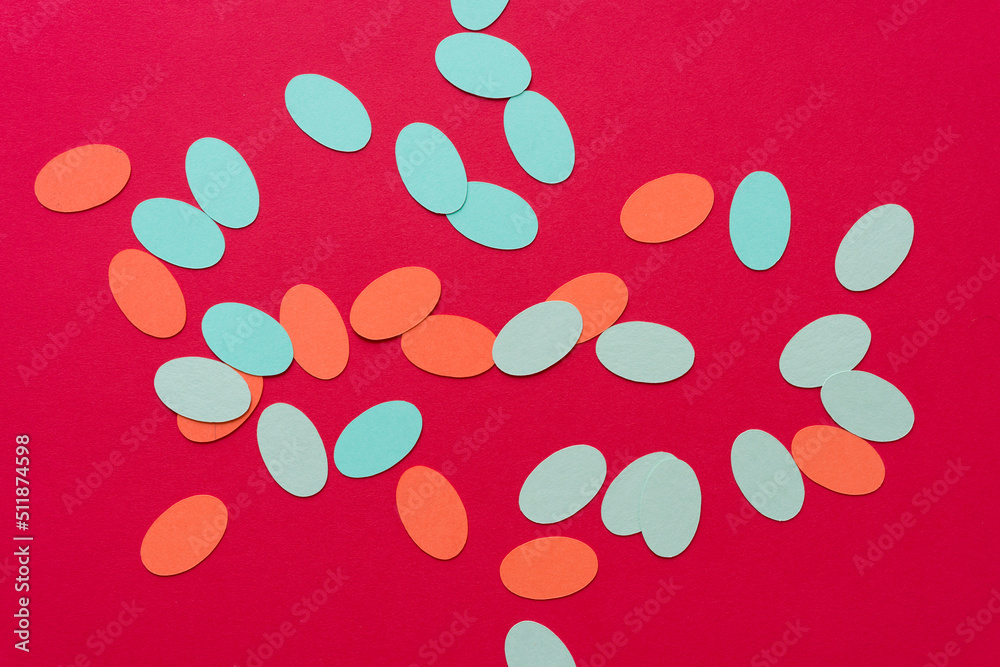 orange and green paper ovals scattered over a red paper background orange and green paper ovals scattered over a red paper background