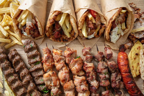 Greek street food, gyro sliced meat pita bread wrap, chiken and pork souvlaki skewer, overhead photo