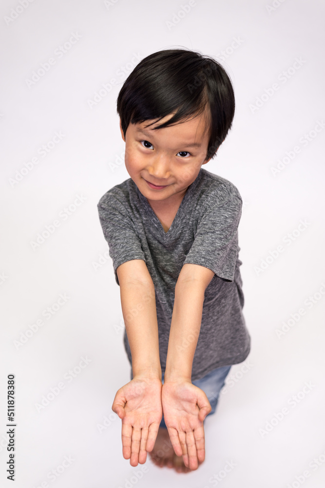 Boy wearing jeans and a gray tee in various poses, such as standing or sitting on a chair