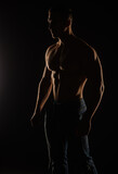 Silhouette of topless guy posing in studio while standing