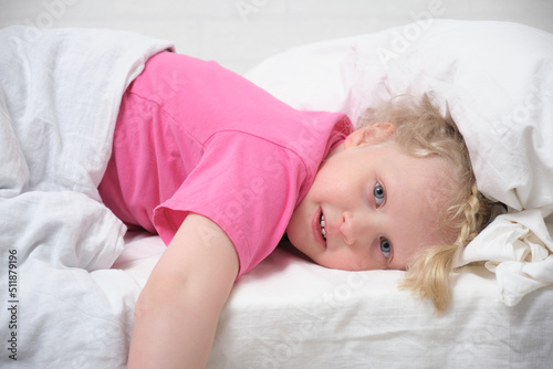 cute girl with blond hair and a pink t-shirt just woke up