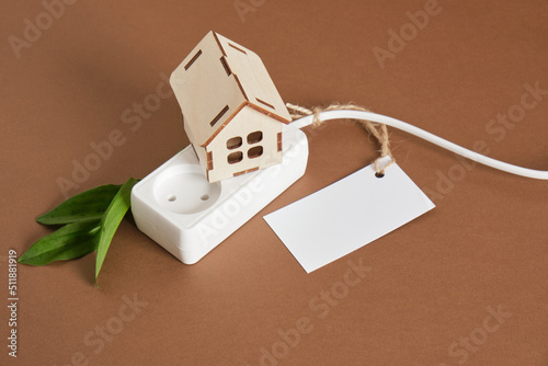 wooden house model, network filter with sockets and leaf, tag for logotype and test, copy space, eco energy concept