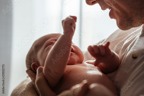 Newborn baby in dad's arms at home, attention to detail, close-up. The concept of caring and love. © KseniaJoyg