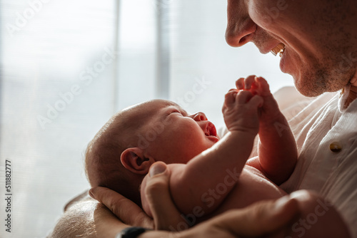 Newborn baby in dad's arms at home, attention to detail, close-up. The concept of caring and love.