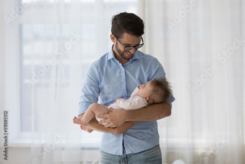 Young caring daddy holding on arms his infant baby daughter, looking with affection enjoy moments of tenderness, feeling unconditional love. Babyhood, Fathers Day, happy fatherhood, cherish concept