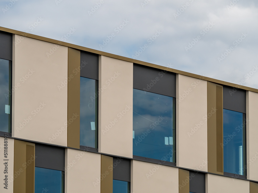 Modern building architecture. Exterior of a contemporary building with beige elements and windows on the facade. New office house in the city with a minimalistic business style. Modern building architecture. Exterior of a contemporary building with beige elements and windows on the facade. New office house in the city with a minimalistic business style.