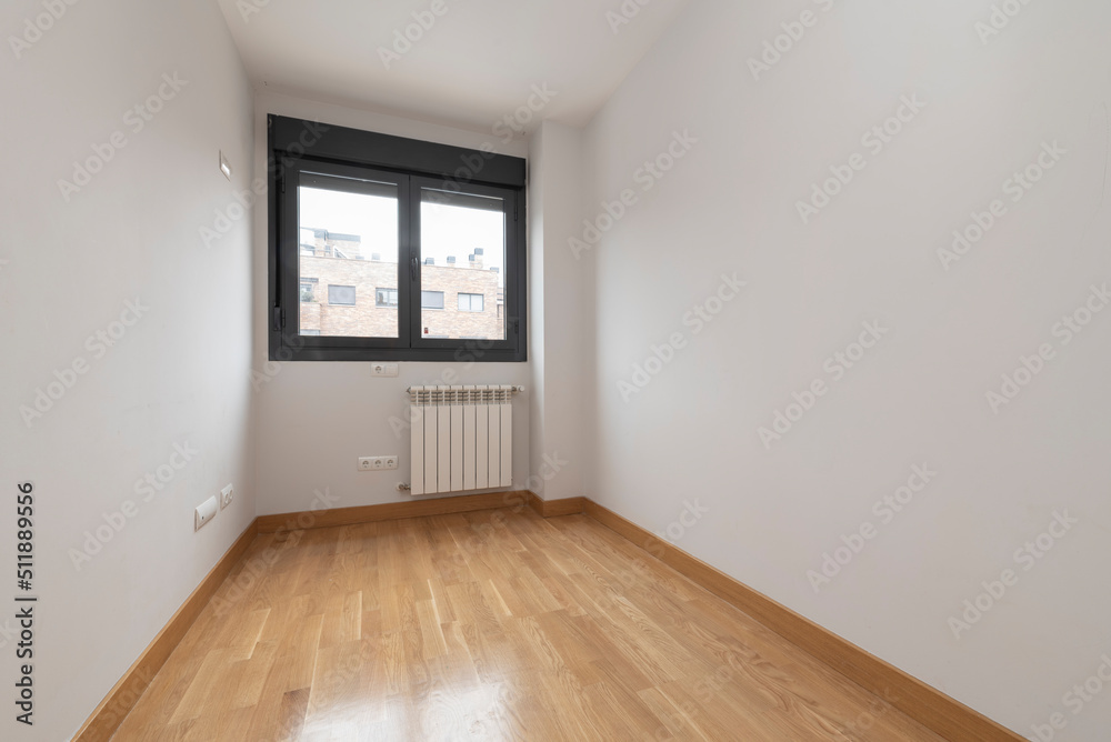 Empty bedroom with black aluminum window, white radiator and plain white painted walls