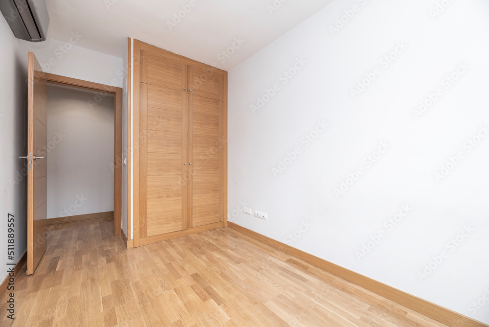 Empty bedroom with two door oak built in wardrobe, matching wooden flooring and white painted walls Empty bedroom with two door oak built in wardrobe, matching wooden flooring and white painted walls