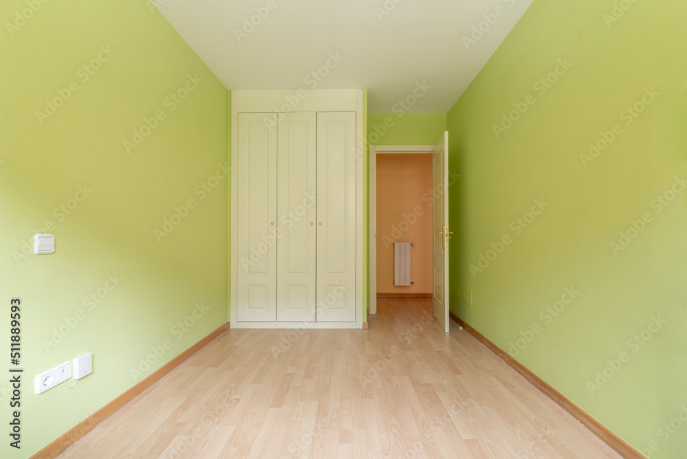 Empty room with white wooden three-section built-in wardrobe, green painted walls and light wooden floor Empty room with white wooden three-section built-in wardrobe, green painted walls and light wooden floor