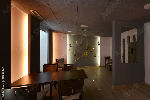 Dining room of a modern restaurant with neon lights and a dark wood table with matching chairs and oak floorboards