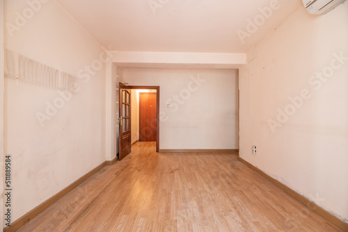 Empty living room with wooden floors, wooden doors with glass and plain white painted walls