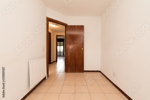 Empty room with varnished plywood door and ceramic tile flooring