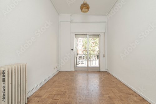 Empty living room with oak parquet and exit to a terrace through an aluminum window with sliding leaves