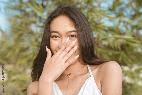 A pretty Filipino woman blushing while flirting with someone. Signs of physical attraction during a date. Reaction from flattery.