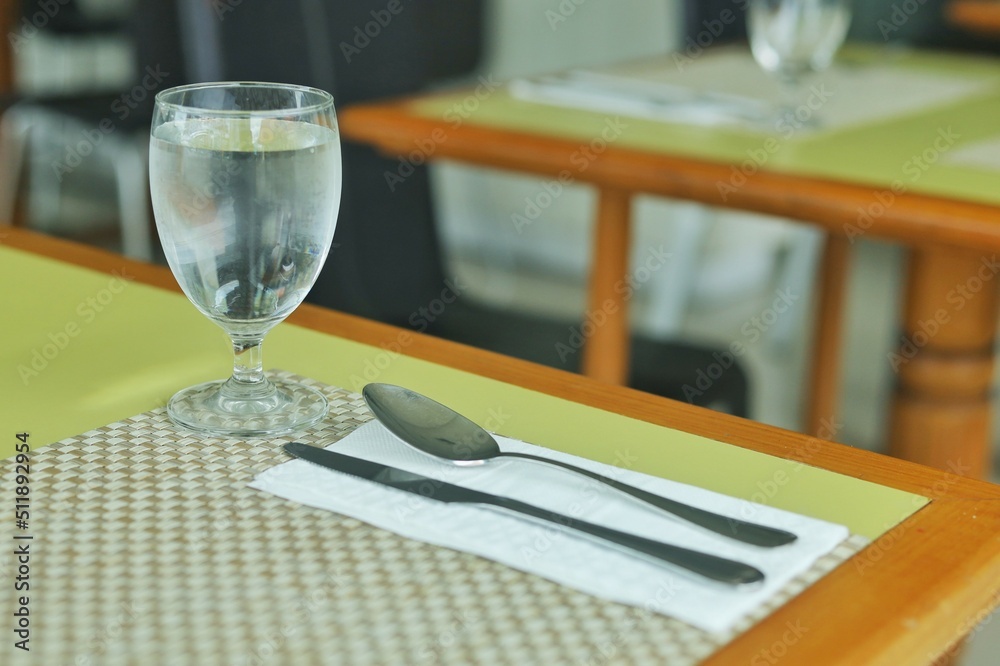 The set of utensil such as glass fork and spoon set on the table for having meal at restaurant or hotel.