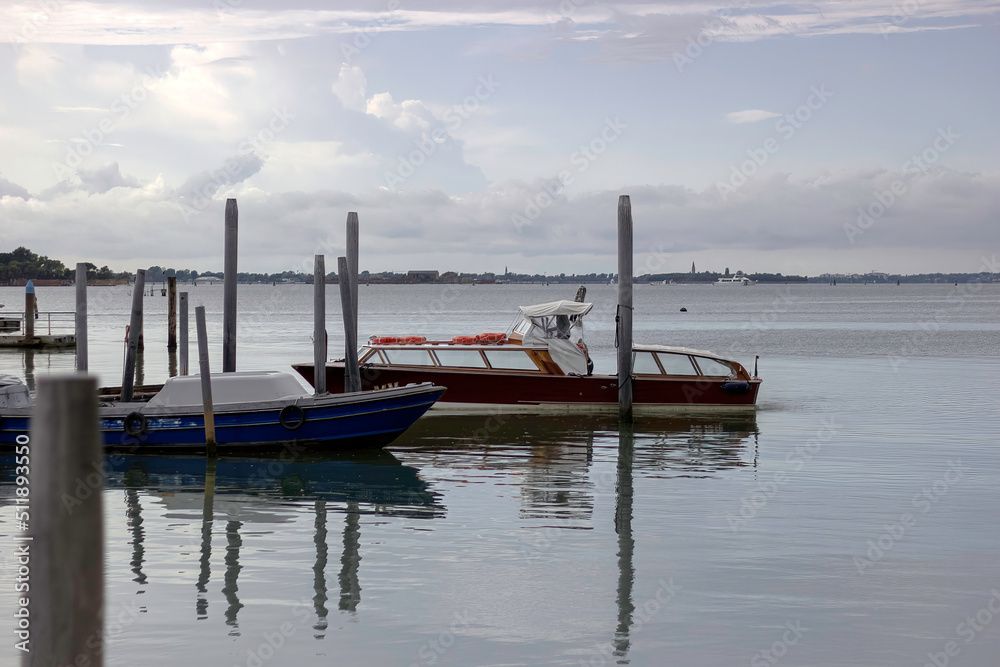 Venice, Italy - Motor boats and gondola docked in the island of venetia against dramatic sky