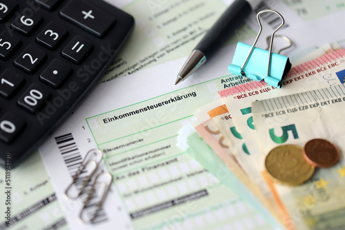 German income tax return form with pen and european euro money bills lies on accountant table close up. Taxpayers in Germany using euro currency to pay taxes photo