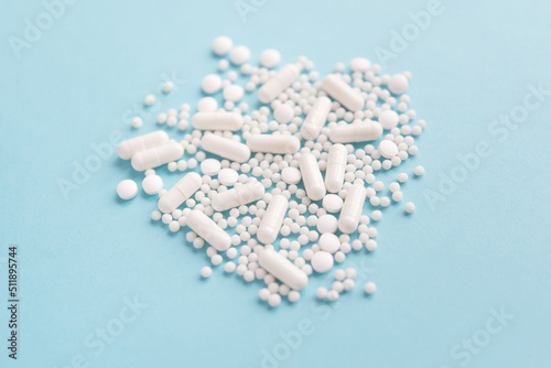  White pills on a blue pastel background. Capsules and round pills close-up. health care and medicine.