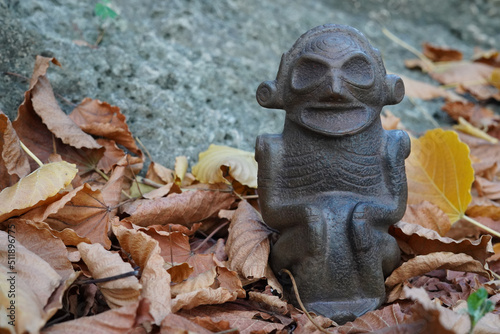 Taino Antique Stone Cemi Idol Figure sitting on the ground on top of dry leaves. Taino Indian Mythology. photo