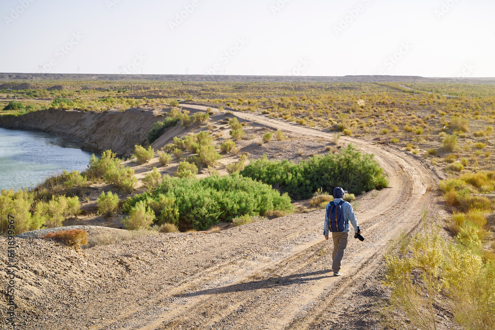 asian male photographer walking in gobi desert
