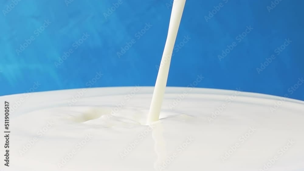 Milk pours on the surface of milk close-up with beautiful splashes and drops on a blue background. 4k raw slow motion video 60 fps. Filmed on high speed cinema camera, 1000fps. Milk pours on the surface of milk close-up with beautiful splashes and drops on a blue background. 4k raw slow motion video 60 fps. Filmed on high speed cinema camera, 1000fps.